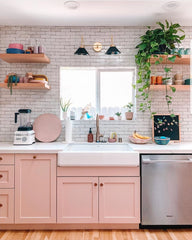 Pink modern kitchen with handmade subway tile, open shelving, and plants