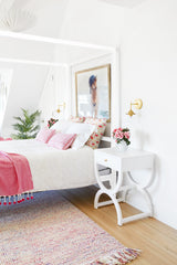 feminine bedroom design with white nightstands, fresh pink flowers, and pink linens