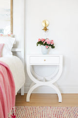 feminine bedroom design with white nightstands, fresh pink flowers, and pink linens