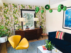 eclectic living room with floral wallpaper, antique buffet, mid century modern inspired furniture, and a bold blue velvet sofa.  Includes a bright green mid century modern style chandelier by Sazerac Stitches