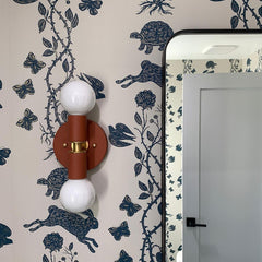 terra cotta wall sconce on patterned navy and cream wallpaper