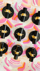 Collection of black and brass thalia sconces on a colorful pink and orange abstract background