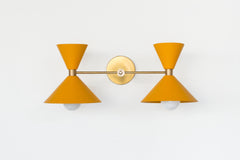 brass and mustard yellow mid century modern wall sconce with two shades.  Colorful bathroom light fixture