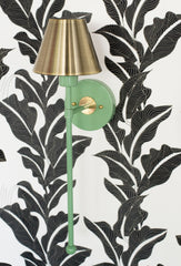 Vintage green and brass colorful bathroom wall sconce on a black and white floral wallpaper