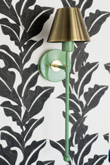 Vintage green and brass colorful bathroom wall sconce on a black and white floral wallpaper