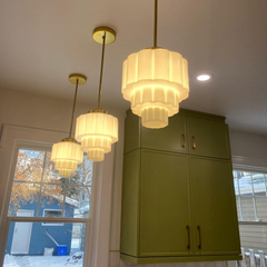 Lit up wedding cake pendant lights in a green kitchen