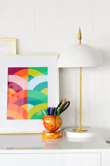 White and brass modern desk lamp with colorful art and a marbled pencil cup