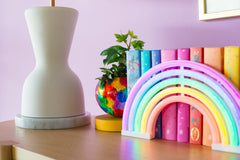 Cream and marble table lamp in a purple living room with rainbow books and decor