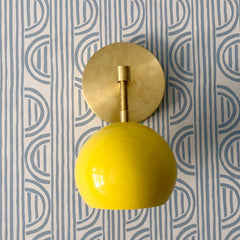 Yellow and brass sconce on patterned wallpaper bathroom wall