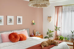 Boho bedroom with pink, peach, rust accents with a contrasting green loa sconce