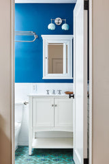 blue bathroom design with cobalt blue walls, mint flooring, and mint wall sconce.  Chrome accent metals