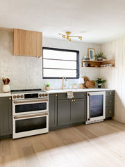 Neutral Kitchenette area with dark cabinets, white tile awlls, brass accents, and wood details