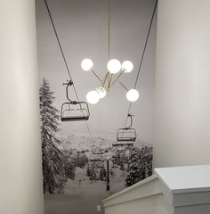Brass chandelier on a stairwell with a ski lift mural